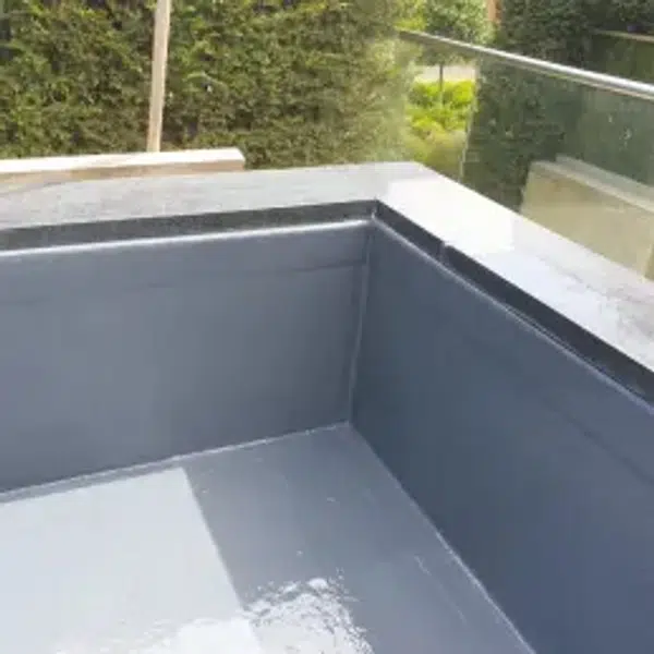 "Worker applying waterproof liquid roofing membrane to protect a concrete roof using a squeegee."